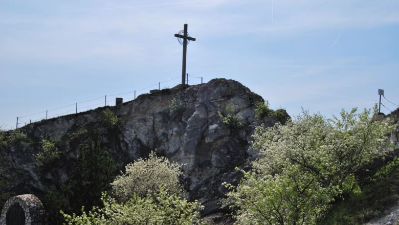 Kleinschweinbarther Kreuzberg, © Gemeinde Drasenhofe Ein Kreuz steht auf einem Hügel mit blühenden Bäumen im Vordergrund.