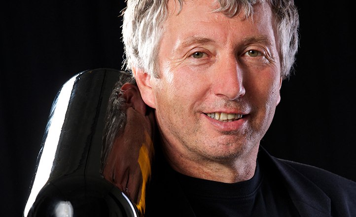 Winzer, © Weinrieder Mann mit grauen Haaren hält eine große Weinflasche auf der Schulter.