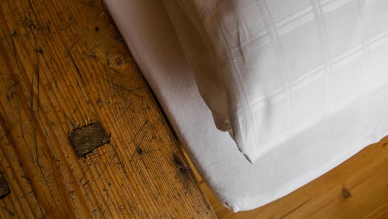 Klinger's guest house, © Astrid Bartl Close-up of a rustic wooden table next to a bed with white bed linen.