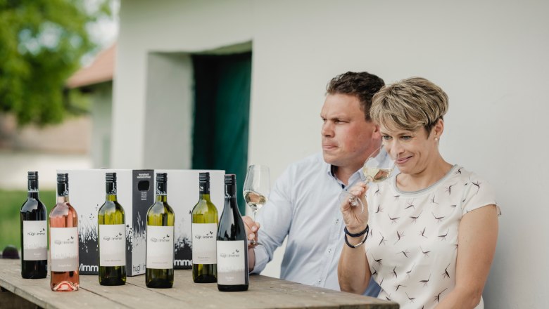 Weinverkostung, © Michael Reidinger Zwei Personen sitzen an einem Tisch mit Weinflaschen und probieren Wein.