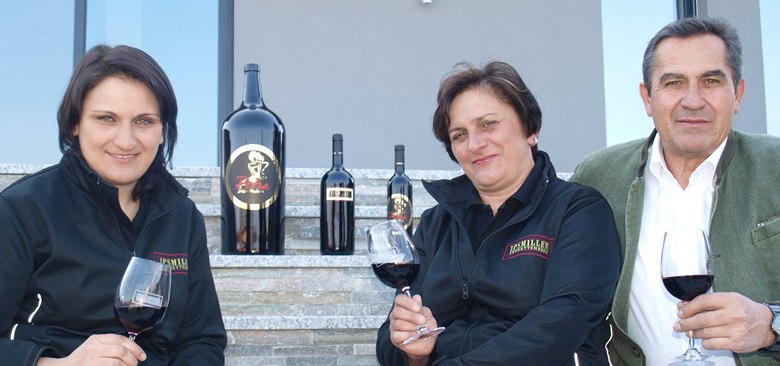 Familie Ipsmiller, © Weingut Ipsmiller Drei Personen sitzen auf Treppenstufen mit Weingläsern und Weinflaschen.