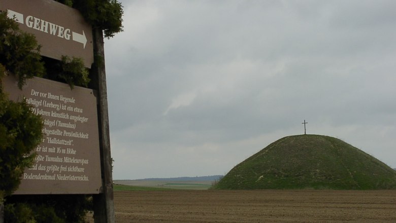 Leeberg, © Gemeinde Großmugl Ein Hügel mit einem Kreuz auf der Spitze, daneben ein Schild mit der Aufschrift 'Gehweg'.