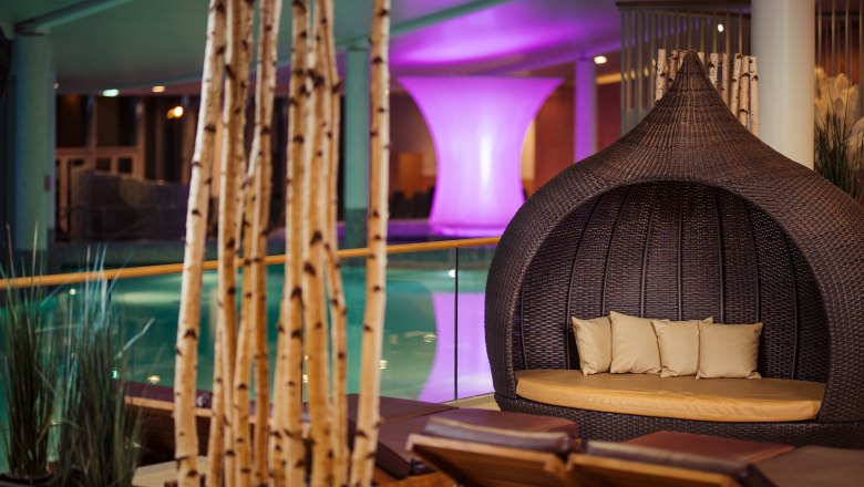Thermenbereich, © Therme Laa Entspannungsbereich mit Liegen und Korbsessel in einem Spa.