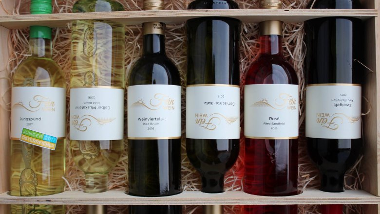 Wine assortment, © Familie Fein Six bottles of wine in a wooden crate with straw.