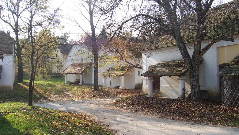 Kellerviertel Loamgrui, © Gemeinde Unterstinkenbrunn Historische Weinkeller im Kellerviertel Loamgrui, umgeben von Bäumen im Herbst.