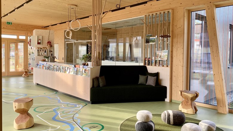 Foyer des March-Thaya-Zentrums, © Ruth Trinkler Innenansicht eines modernen Foyers mit Holzelementen, einer Sitzbank und dekorativen Steinen auf dem Boden.
