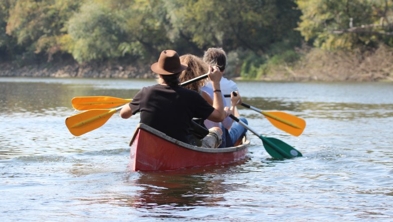 Flussabenteuer, © Ralph Höbinger Drei Personen paddeln in einem roten Kanu auf einem Fluss.