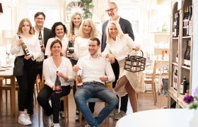 Das Prechtl-Team, © Renate Kowanz Gruppe von Menschen in einem Raum mit Weinflaschen.