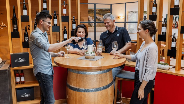 Wine tavern & Humer winery, © Markus Knell Four people stand around a round table made from a wine barrel, while one person pours wine.