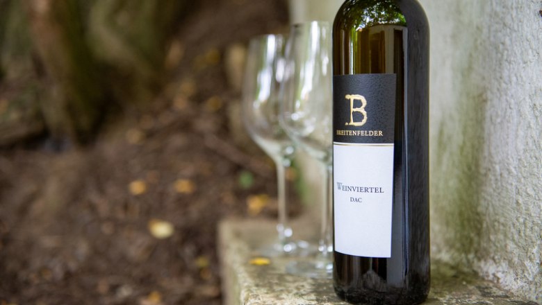 The best wines, © Tonality Wine bottle with two empty glasses outside.