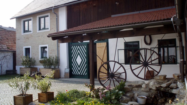 Viticulture and wine tavern Ullmann, © Ullmann Traditional building with wooden roof and decorative wagon wheels in the courtyard.