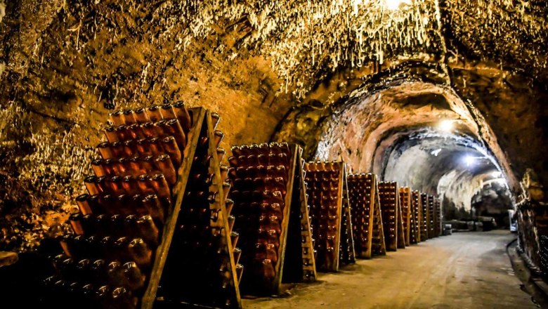 The champagne cellar, © Gut Hardegg A champagne cellar with bottles in wooden racks, illuminated by warm light.