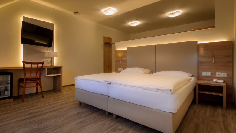 City Hotel Doppelzimmer, © Markus Jung, MJM Photography Modernes Hotelzimmer mit Doppelbett, Schreibtisch, Stuhl und Fernseher.