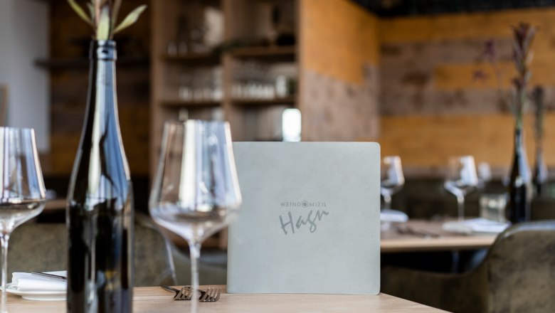 Sklenice na víno, © Stefanie Winter Prostřený stůl v restauraci se sklenicemi na víno, lahví vína a jídelním lístkem.