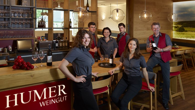 The Humer family team spoil their guests at the wine tavern, © Peter Ableidinger Employees of a winery pose in a modern wine tavern.