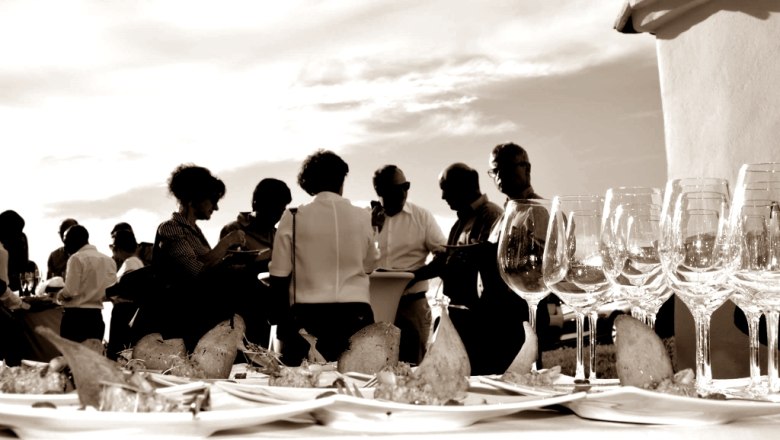 In der Kellergasse, © Weingut A+A Mayer Menschen bei einer Veranstaltung im Freien mit Weingläsern und Snacks auf einem Tisch.