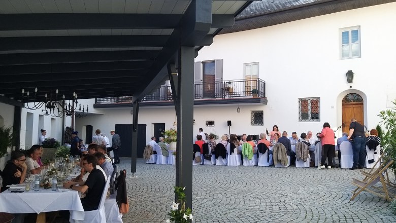 Tafeln im Weinviertel, © Weinviertel Tourismus GmbH Menschen sitzen an langen Tischen in einem gepflasterten Innenhof bei einer Veranstaltung.