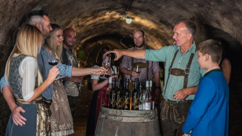 Winery Küssler, © Winzerhof Küssler A group of people in traditional dress at a wine tasting in a wine cellar.