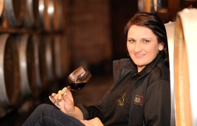 Winzerin Petra Ipsmiller, © Weingut Ipsmiller Frau mit Weinglas in einem Weinkeller.