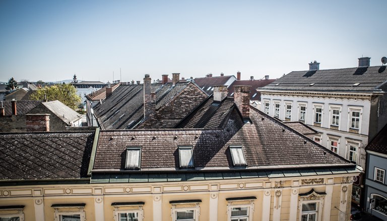 Room view, © flotographix View of the roofs of the neighboring buildings and blue sky.