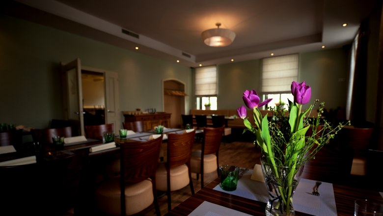 Moravian Embassy, © tonality A stylishly furnished room with laid tables and a bouquet of purple tulips in the foreground.