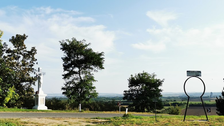 Zeißlkreuz, © Weinstraße Weinviertel Landschaft mit Kreuz und Seefeld-Kadolz Schild.