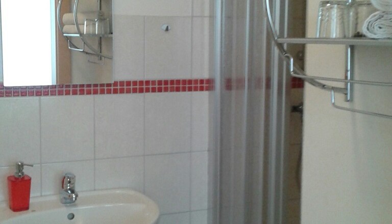 Bad, © © Bianca Waysmayer Ein Badezimmer mit Waschbecken, Spiegel, Dusche und Handtuchregal.