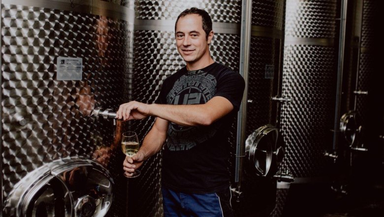 Johannes Hofmeister, © Weingut Hofmeister Mann zapft Wein aus einem Edelstahltank in einem Weinkeller.