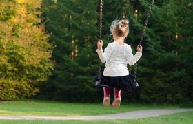 Spielplatz, © pixabay Ein Kind schaukelt im Freien, umgeben von Bäumen und grünem Gras.