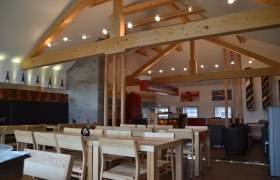 Weinbau Müllner, © Michael Müllner Innenansicht eines modernen Weinguts mit Holzbalken, Tischen und Stühlen.
