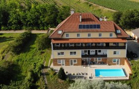Pension Rudi, © Pension Rudi Luftaufnahme eines großen Hauses mit Pool und Solarpanelen, umgeben von Weinbergen.