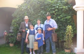 Familie Graf, © Johannes Graf Familie in traditioneller Kleidung vor einem Weinstock.