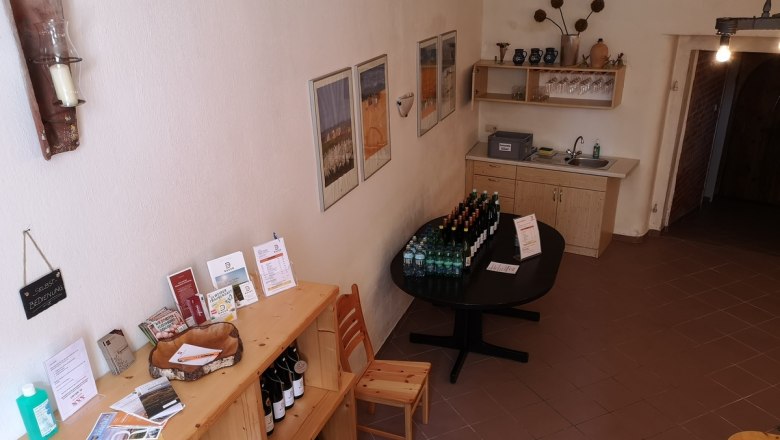 Bauers Kellerrast, © Weinbau Bauer Innenansicht eines rustikalen Kellers mit Selbstbedienungstheke und Getränken.