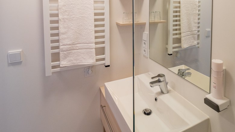 Badezimmer, © freilich / IsaBella Fritsche Modernes Badezimmer mit Waschbecken, Spiegel und Handtuchhalter.