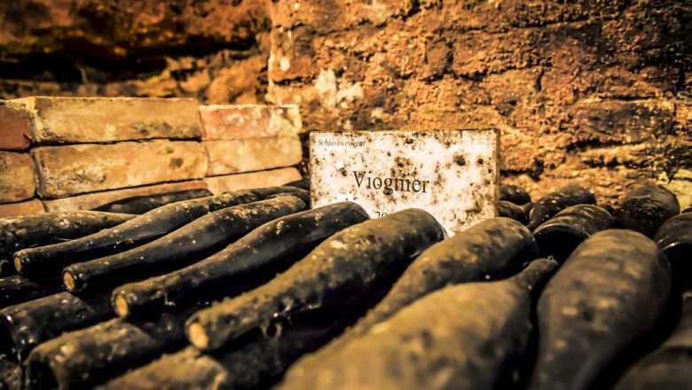 Matured Viognier in the estate cellar, © Gut Hardegg Dusty wine bottles in the cellar with a sign saying 'Viognier'.