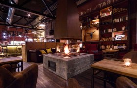 Living Room, © Derenko GmbH Gemütlicher Raum mit Kamin, Holzmöbeln und Bücherregalen.