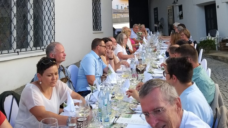 Tafeln im Weinviertel, © Weinviertel Tourismus GmbH Menschen sitzen an einem langen Tisch im Freien und genießen ein gemeinsames Essen.