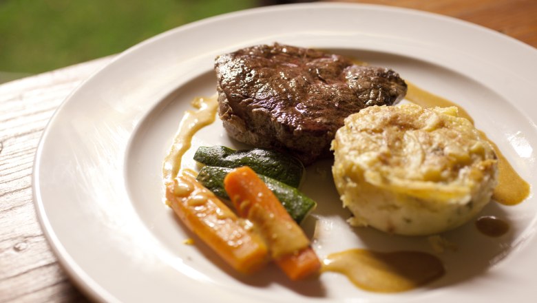 Gute Hausmannskost, © Weinviertel Tourismus GmbH / Wurnig Ein Teller mit einem Stück Fleisch, Gemüse und einer Kartoffelbeilage.