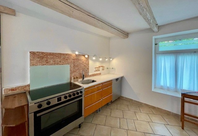 Küche, © Julia Grünschachner Moderne Küche mit Herd, Holzschränken und Fliesenboden.