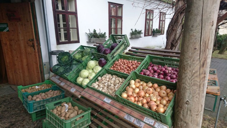 Frisches Gemüse, © Josef Popp Gemüsestand mit verschiedenen Sorten von Kohl, Zwiebeln und Kartoffeln in grünen Kisten vor einem Gebäude.