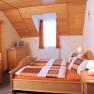 Cozy guest room with wooden furniture, double bed, small table, TV and sloping ceiling.