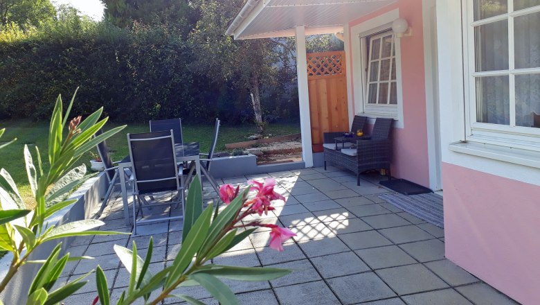 Terrasse mit Gartenmöbeln und rosa Hausfassade.
