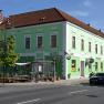 Green building with hotel and caf&eacute; signs on a street corner.