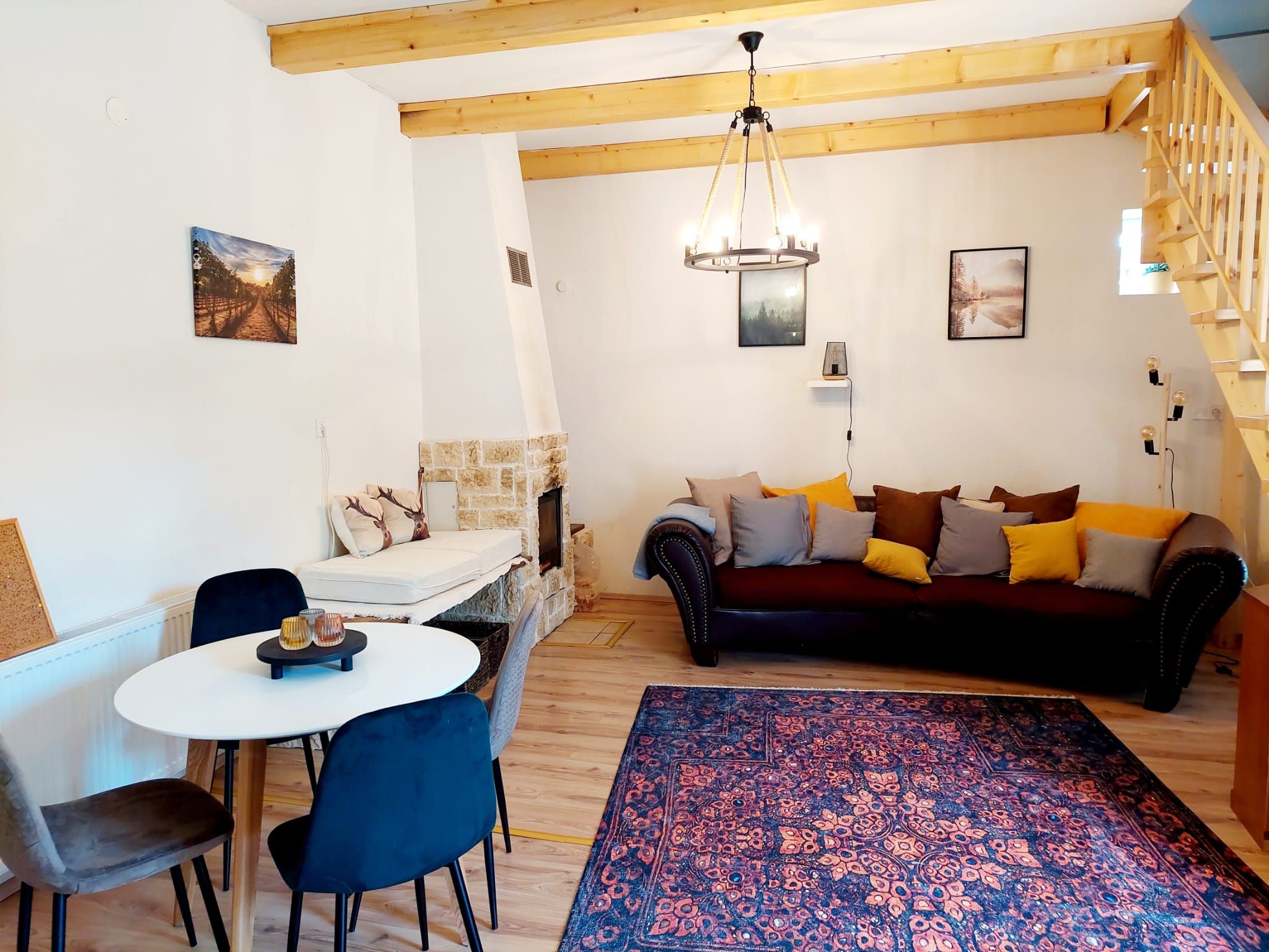 Gemütliches Wohn-Esszimmer mit Holzbalken, Sofa, Esstisch und Kamin.