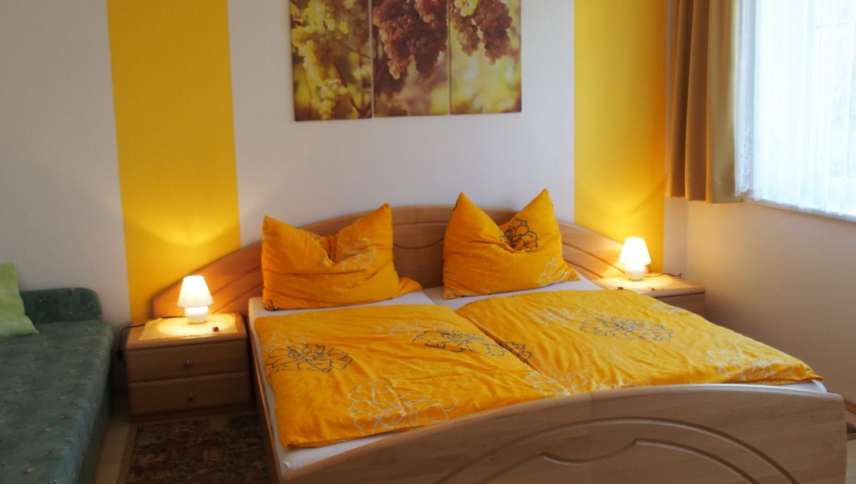 Gemütliches Schlafzimmer mit gelber Bettwäsche und warmem Licht.