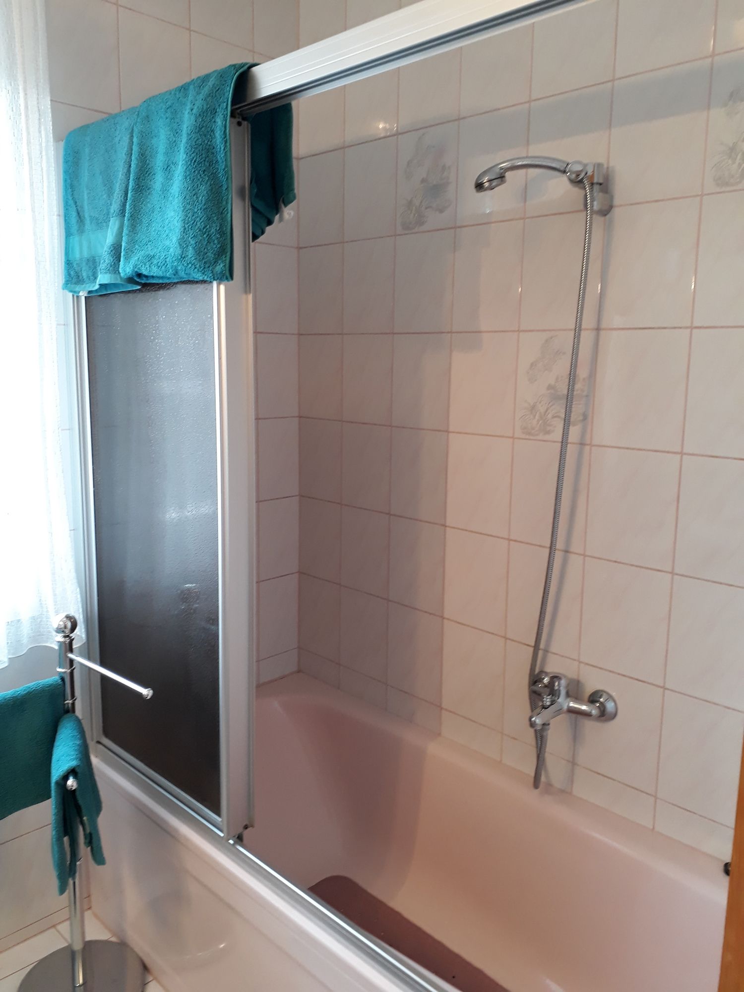 Badezimmer mit Badewanne, Duschvorhang und blauen Handtüchern.