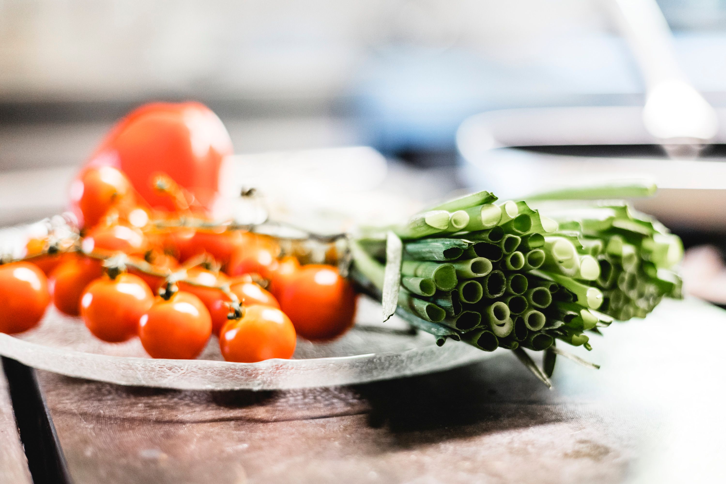 Nahaufnahme von frischen Kirschtomaten und Frühlingszwiebeln auf einem Teller.