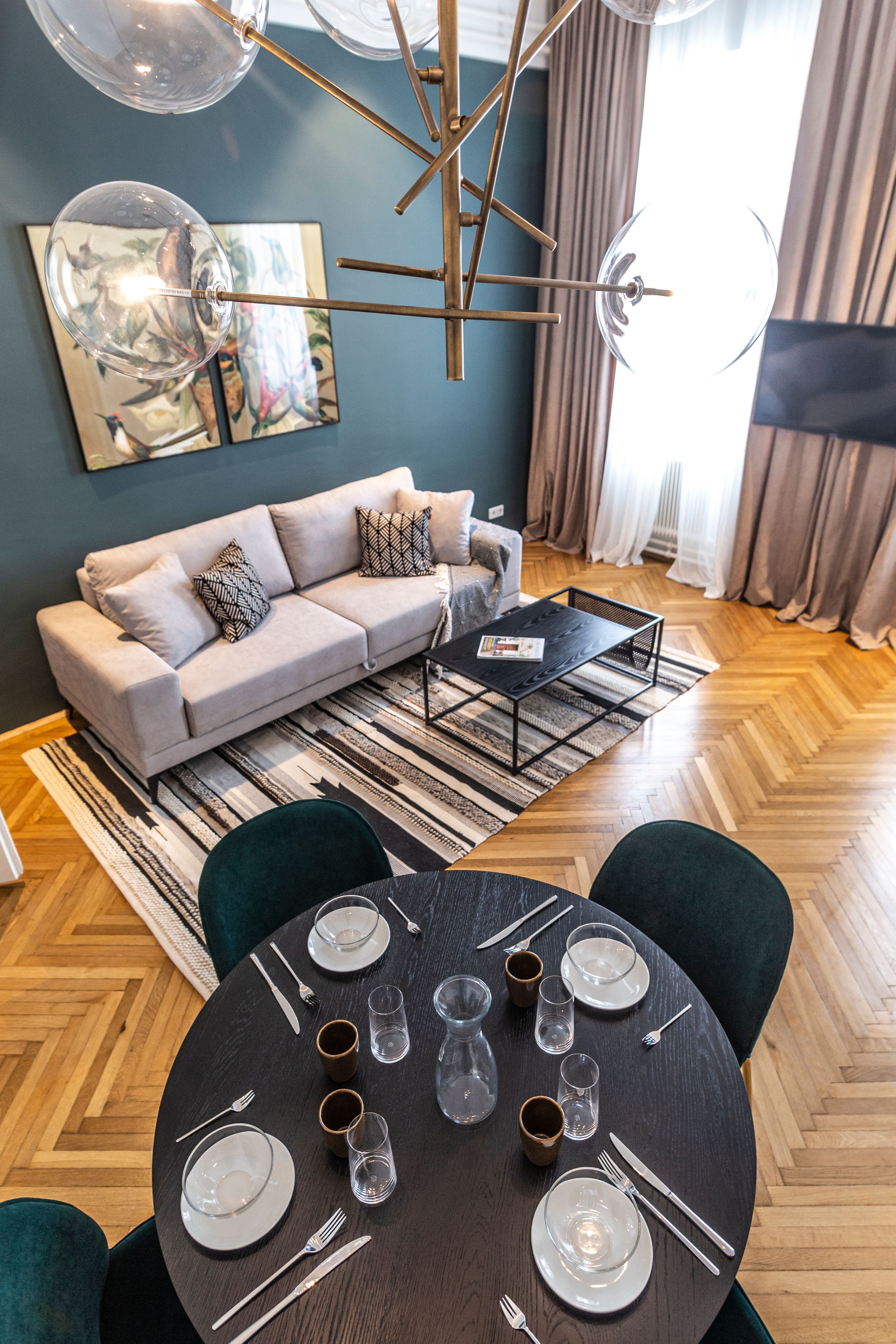 Modernes Wohnzimmer mit Sofa, Couchtisch, Teppich und Esstisch mit Gedeck.