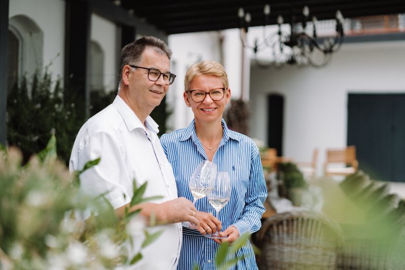 Zwei Personen stehen draußen und halten Weingläser.