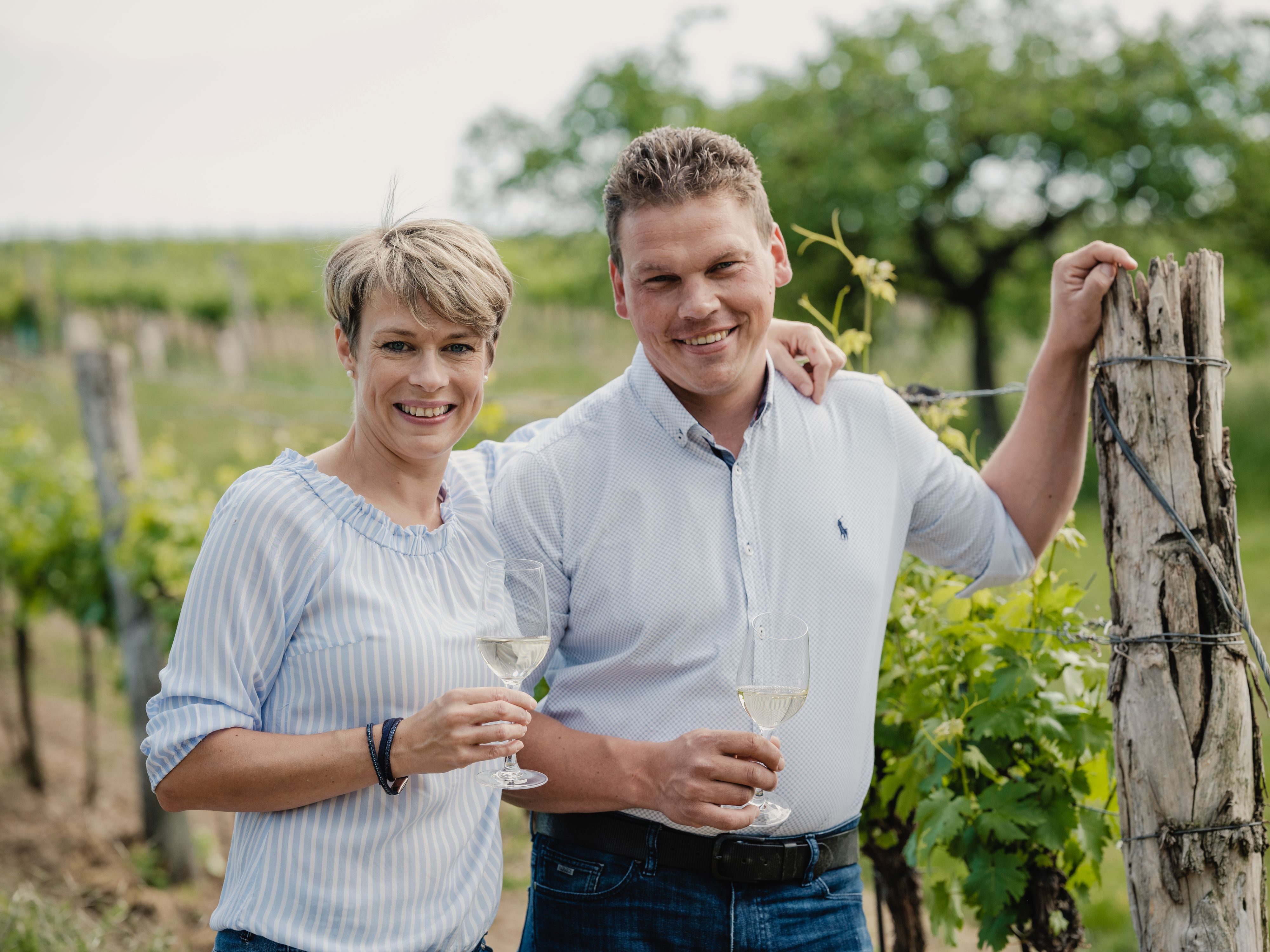 Zwei Personen in einem Weinberg mit Weingläsern.